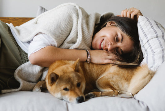 a woman laying down with her smal brown dog 
